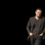 Portrait of Kit Logan, leaning against the side of the image.