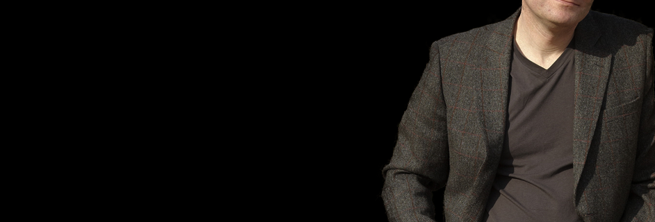 Portrait of Kit Logan, leaning against the side of the image.