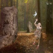 Young girl leaping to touch a fairy flying above her. Forest setting with standing stones.
