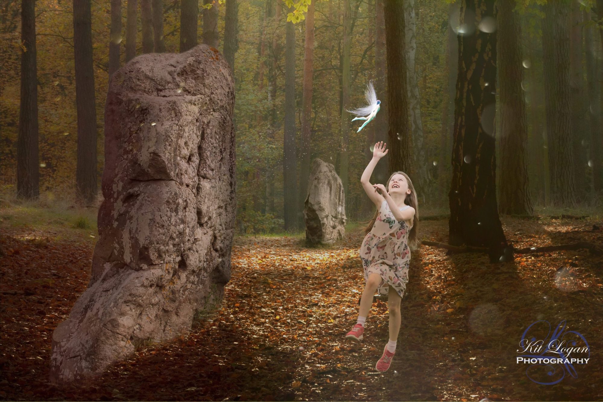 Young girl leaping to touch a fairy flying above her. Forest setting with standing stones.