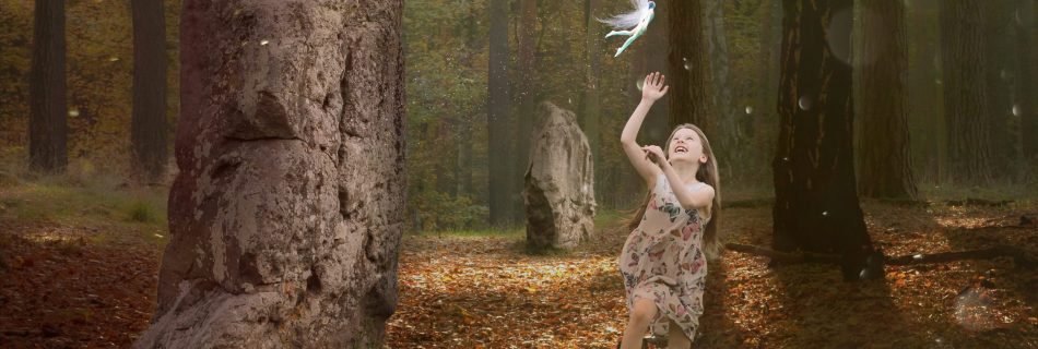 Young girl leaping to touch a fairy flying above her. Forest setting with standing stones.