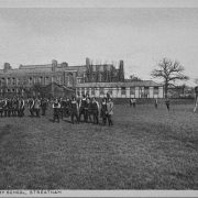 Old photo of school girls in field standing in front of school