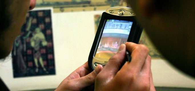 Students using mobile phone to study images at a museum