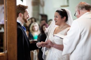 Image of a couple getting married in a church, view taken from behind the vicar towards the congregation.