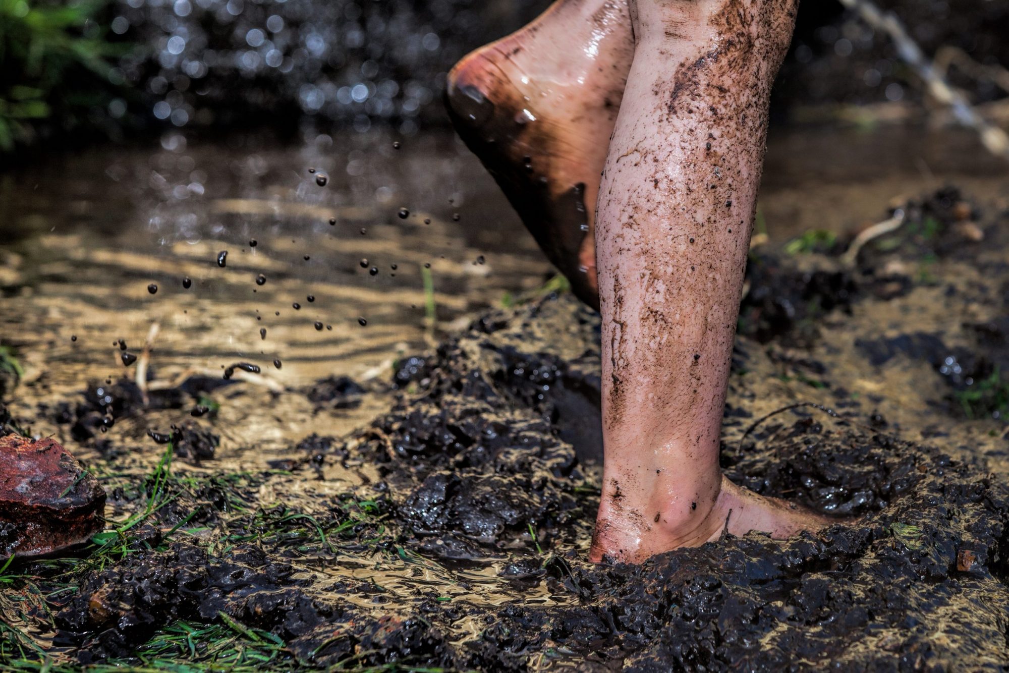 Childs bare feet and legs covered with mud.