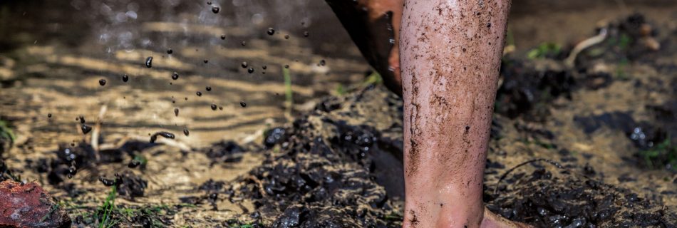 Childs bare feet and legs covered with mud.