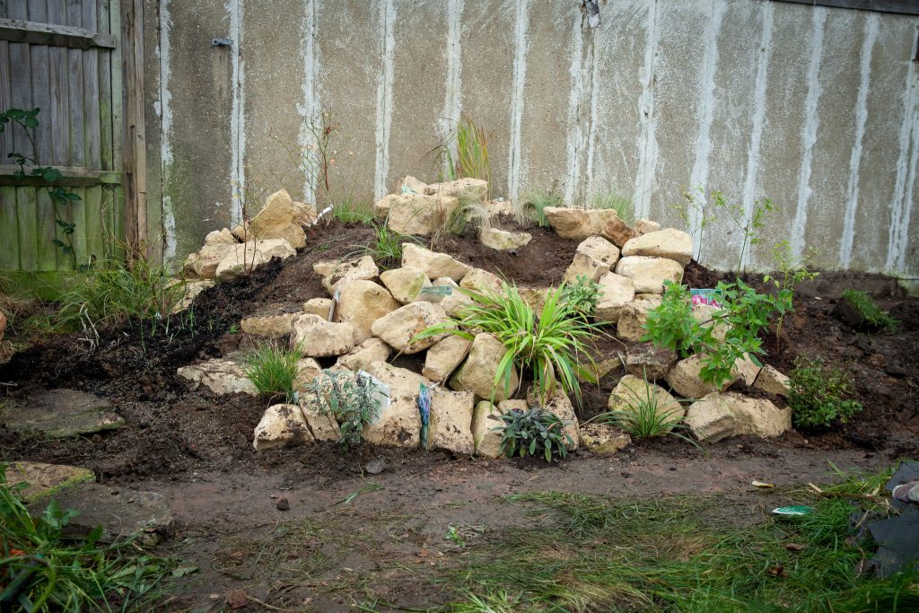 Soil mound with pale coloured rocks and some plants interspaced in between.