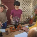 Two children looking at a Wimshurst machine with Peter Logan.